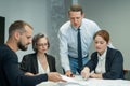 The boss gives instructions to three employees in the office conference room. Brainstorming engineers and architects.