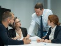 The boss gives instructions to three employees in the office conference room. Brainstorming engineers and architects.