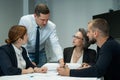 The boss gives instructions to three employees in the office conference room. Brainstorming engineers and architects.