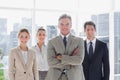 Boss with his arms folded standing with smiling colleagues behind