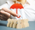 Boss holding a red umbrella and defending his team with a gesture of protection. Security and safety in a business team. Life Royalty Free Stock Photo