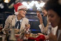 Boss lady wearing santa hat with glasses having a good time at business dinner at the end of successful year with colleagues