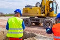 Boss oversees, controlling excavator until is digging on building site