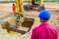 Boss oversees, controlling excavator until is digging on building site