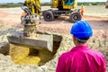 Boss oversees, controlling excavator until is digging on building site