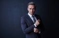 Bossed up style. Studio portrait of a stylish and mature businessman standing against a dark background. Royalty Free Stock Photo