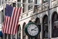 Boston, MA USA - Shopping Mall Store front with american flag waving with a big clock beside it Royalty Free Stock Photo