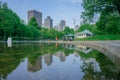 Frog Pond in Boston Common with reflection of buildings and locals walkings and resting by the water