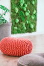 Botanical relaxing living room with green wall and bright knitted pouf