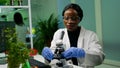 Botanist woman looking at test sample under microscope observing genetic mutation Royalty Free Stock Photo