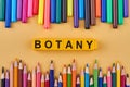 Botany word made from plastic cubes in frame from colored pencils and felt pens. Royalty Free Stock Photo