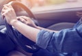 Both hands of woman wearing a blue jean shirt gripping wheel driving right hand drive car