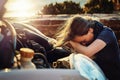 Both her and her car are going through a breakdown. a young woman looking upset after breaking down on the roadside. Royalty Free Stock Photo