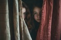 both peeking out from behind a curtain side by side Royalty Free Stock Photo