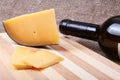 Botle with red wine grapes and chees on wooden table.