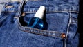 Bottle of alcohol spray in the pocket of blue jeans.