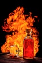 . A bottle of alcoholic drink with a reclining glass on a wooden table against the background of a flame of fire. Creative studio Royalty Free Stock Photo