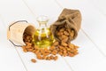 Bottle of almond oil and almonds on white wooden background. Royalty Free Stock Photo