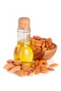 Bottle of almond oil and almonds in a wooden bowl isolated on white background Royalty Free Stock Photo