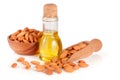 Bottle of almond oil and almonds in a wooden bowl and scoop isolated on white background