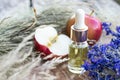 Bottle of apple essential oil and fresh apples on a wooden table. Essential oil is used to fill lamps, perfumes and in cosmetics