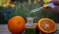 bottle of aromatic essence and fresh orange on the background of nature. Royalty Free Stock Photo