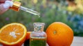 bottle of aromatic essence and fresh orange on the background of nature. Royalty Free Stock Photo