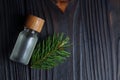 Bottle of aromatic essential oil and pine branch on wooden table, top view. Space for text