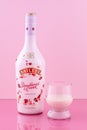 A bottle of Baileys with glass. Strawberries and cream. Limited edition. Liquor on a pink background. Alcohol drink. Illustrative Royalty Free Stock Photo