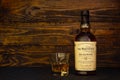 A bottle of Balvenie Doublewood 12 Years Old Scotch Whisky and a glass with ice on a dark wooden background. Single malt