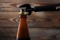 A bottle of beer, made of dark glass with a golden cork, opens with a black opener for beer Royalty Free Stock Photo