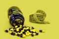 Bottle of black and yellow pills, chain or caffeine pills with tape measure beside, physical activity concept