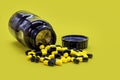 Bottle of black and yellow pills on yellow background, caseia aor caffeine pills used in bodybuilding for muscle mass