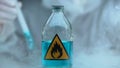 Bottle with blue inflammable liquid in lab, scientist conducting experiment