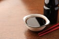 Bottle, bowl with soy sauce and chopsticks on wooden table, closeup. Space for text Royalty Free Stock Photo