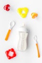 Bottle with breastmilk and infant formula powdered healthy food, spoons and bib on white background top view