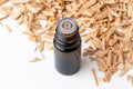 A bottle of cedar essential oil with pieces of cedar wood