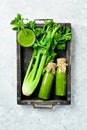 A bottle of celery juice in a box on a stone background. Vegetarian drink. A stalk of fresh celery.