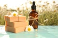 Bottle of chamomile essential oil and soap bars on blue wooden table in field Royalty Free Stock Photo