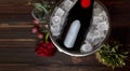 Bottle of champagne in a bucket with ice, rose, pineapple and glasses, on a wooden background with space for text Royalty Free Stock Photo