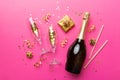 Bottle of champagne with colored glitter, confetti and gift box space for text on colorfull background, top view Royalty Free Stock Photo