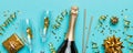 Bottle of champagne with colored glitter, confetti and gift box space for text on colorfull background, top view Royalty Free Stock Photo