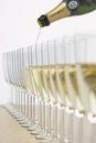 Bottle of champagne filling row of glasses selective focus