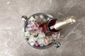 Bottle of champagne with floral ice cubes in bucket on table