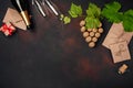 Bottle of champagne, gape bunch of cork with leaves, two wineglass, envelope and gift box on rusty background.