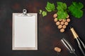 Bottle of champagne, gape bunch of cork with leaves, wineglass, and tablet on rusty background.