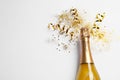 Bottle of champagne with gold glitter, confetti and space for text on white background, top view. Hilarious