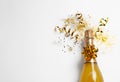 Bottle of champagne with gold glitter, confetti and space for text on white background, top view. Royalty Free Stock Photo