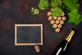 Bottle of champagne, grape bunch of cork with leaves and chalkboard on rusty background