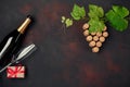 Bottle of champagne, grape bunch of cork with leaves, gift box, wineglass on rusty background